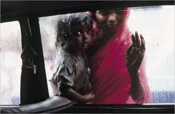 INDIA. Bombay. 1993. Una madre e un bambino chiedono l'elemosina dal finestrino di un taxi durante il monsone